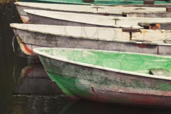 Old grungy rowboats moored in a row, vintage toned photo