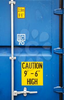 Yellow warning signs on closed gate of standard blue cargo shipping container