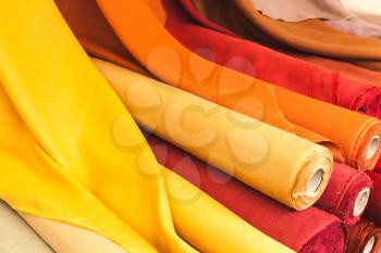 Colorful rolls of natural linen cloth lie on the market counter