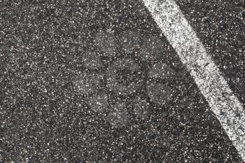 White dividing line on dark gray tarmac, highway road marking. Abstract transportation background texture