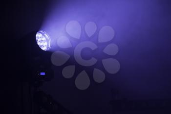 Stage LED spot light with blue beam in smoke, stage illumination equipment
