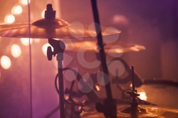 Live rock music background, drummer plays with drumsticks on rock drum set. Warm toned close up photo, soft selective focus