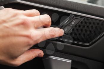 Driver hand pushes door lockers button of luxury crossover car. Close up photo with selective focus