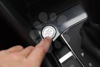 Driver hand pushes engine start stop button. Modern luxury crossover car interior details