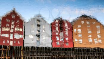 Colorful traditional wooden houses in old town of Trondheim, Norway. Coast of Nidelva river. Reflections pattern in flowing water