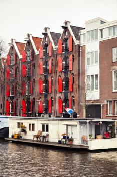 Colorful traditional living houses and houseboats along the canal in Amsterdam, Netherlands. Warm vintage tonal correction filter effect, vertical photo
