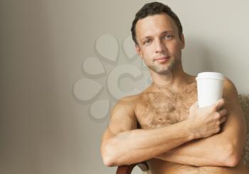 Portrait of young European man sitting with white paper cup of Coffee