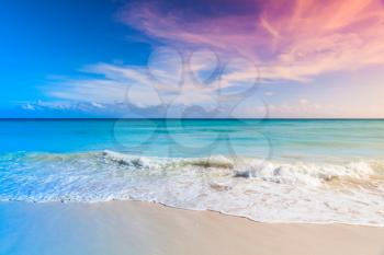 Tropical beach background, white sand and azure shore water under cloudy blue sky. Caribbean Sea coast, Dominican republic, Saona island. Tonal correction, colorful gradient filter effect
