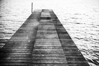 Old empty wooden pier perspective, black and white background photo