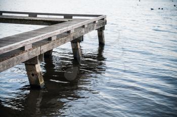 Corner of old wooden pier and blue lake water, background photo
