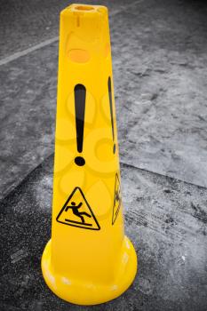 Caution wet floor, yellow warning sign stands on gray asphalt urban ground