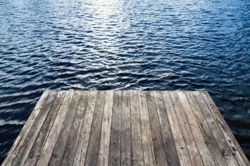 Edge of old wooden pier and blue lake water, background photo