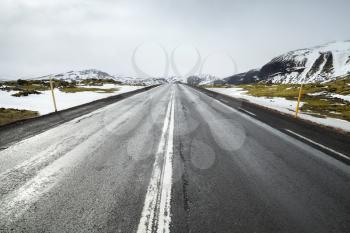 Icelandic road perspetive, rural landscape with snowy mountains on horizon
