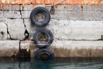Concrete mooring wall with old used tires as a ship bumpers, mooring port equipment