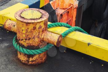 Ships mooring equipment, yellow bollard with ropes mounted in concrete pier