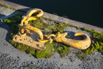 Ships mooring equipment, yellow hooks for ropes mounted in concrete pier