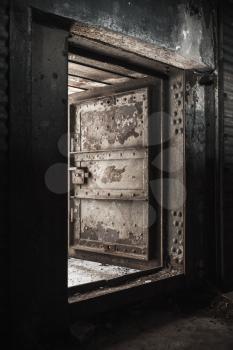 Abstract dark grungy industrial interior with metal wall and open heavy steel door