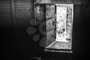 Abstract dark grungy industrial interior with metal walls and open heavy steel door, black and white photo