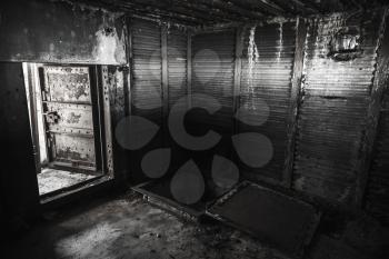 Abstract dark grungy industrial interior with metal walls and open heavy steel door, black and white
