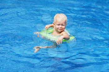 Baby swimming in the blue pool water