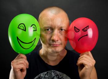 Emotionless man between happy and angry balloons
