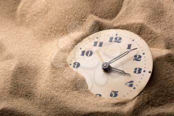 Old alarm clock in sand
