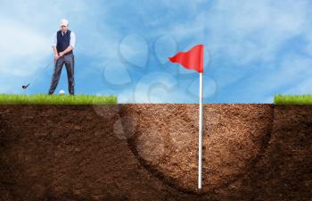 Businessman is hitting the golf ball to the huge hole