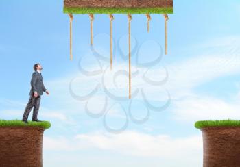 Businessman standing on the grass looks at the ropes overhead