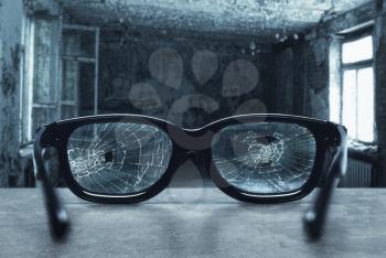 Broken eyeglasses with cracks in an old room