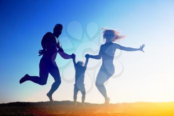 Silhouette of happy family jumping on the beach