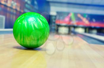 Ball on bowling alley against ten pins