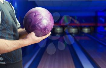 Man holding ball against bowling alley