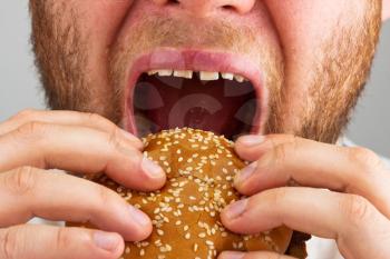 Close-up of bearded man eating juicy hamburger
