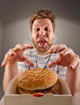 Portrait of happy man with leaking saliva preparing to eat burger