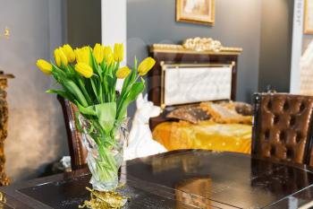Bouquet of yellow tulips stands on the table in the bedroom