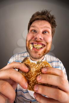 Portrait of expressive fat man chewing hamburger