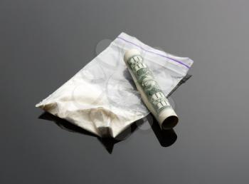 Cocaine in package and one dollar bill on grey