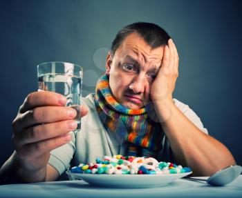 Sad ill man preparing to eat medicines