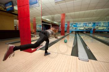 Funny beginner girl playing bowling. Wide angle