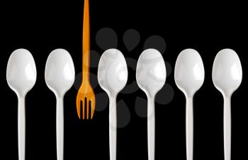 A row of plastic spoons and one yellow fork. Isolated on white