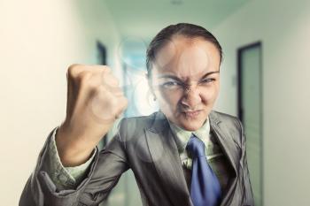 Angry irritated woman clenching her fist in the office