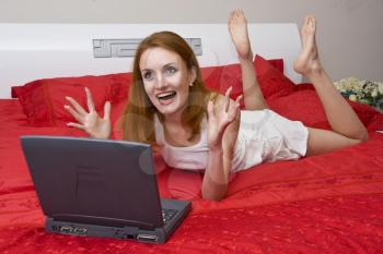 Beautiful woman in red bed with laptop