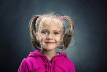 Smiling little girl in rose jacket on grey