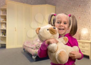 Cute girl at home holding toy bear