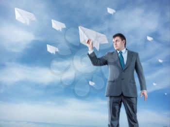 Businessman with big paper plane and isolated on sky background