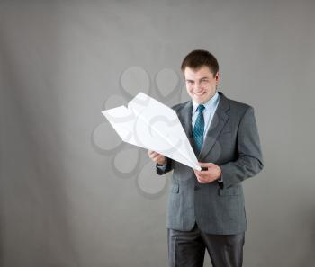 Businessman with white big paper plane isolated in gray