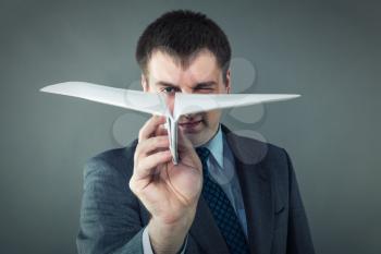 Businessman with white paper plane isolated in gray