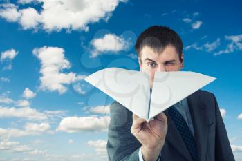 Businessman with paper plane and isolated on sky background