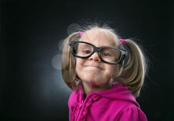 Little girl in funny big spectacles on grey