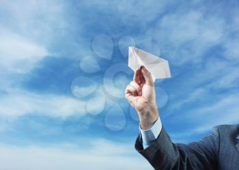 Businessman holding white  paper plane in his hand